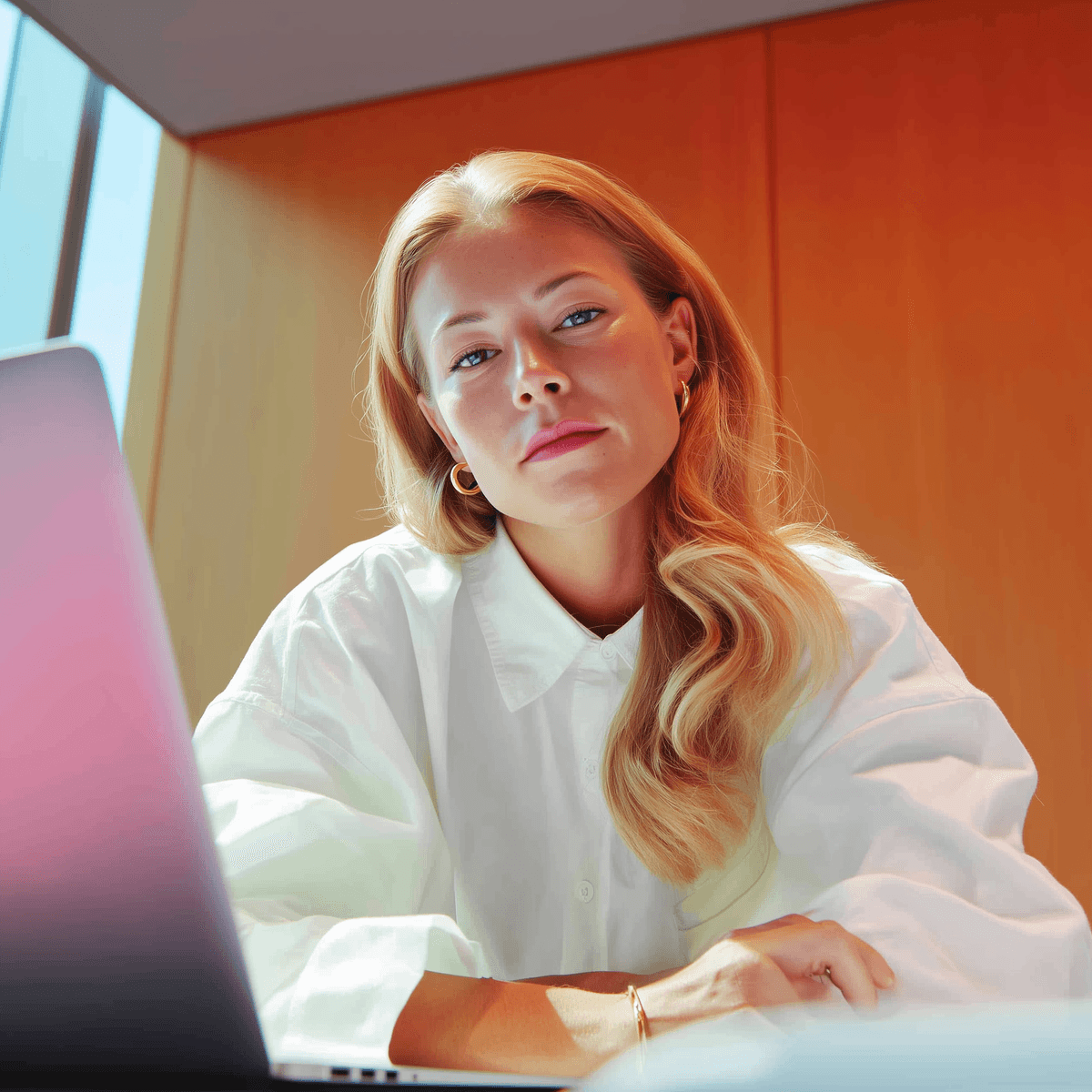 Diseñadora trabajando en una laptop sobre un fondo cálido